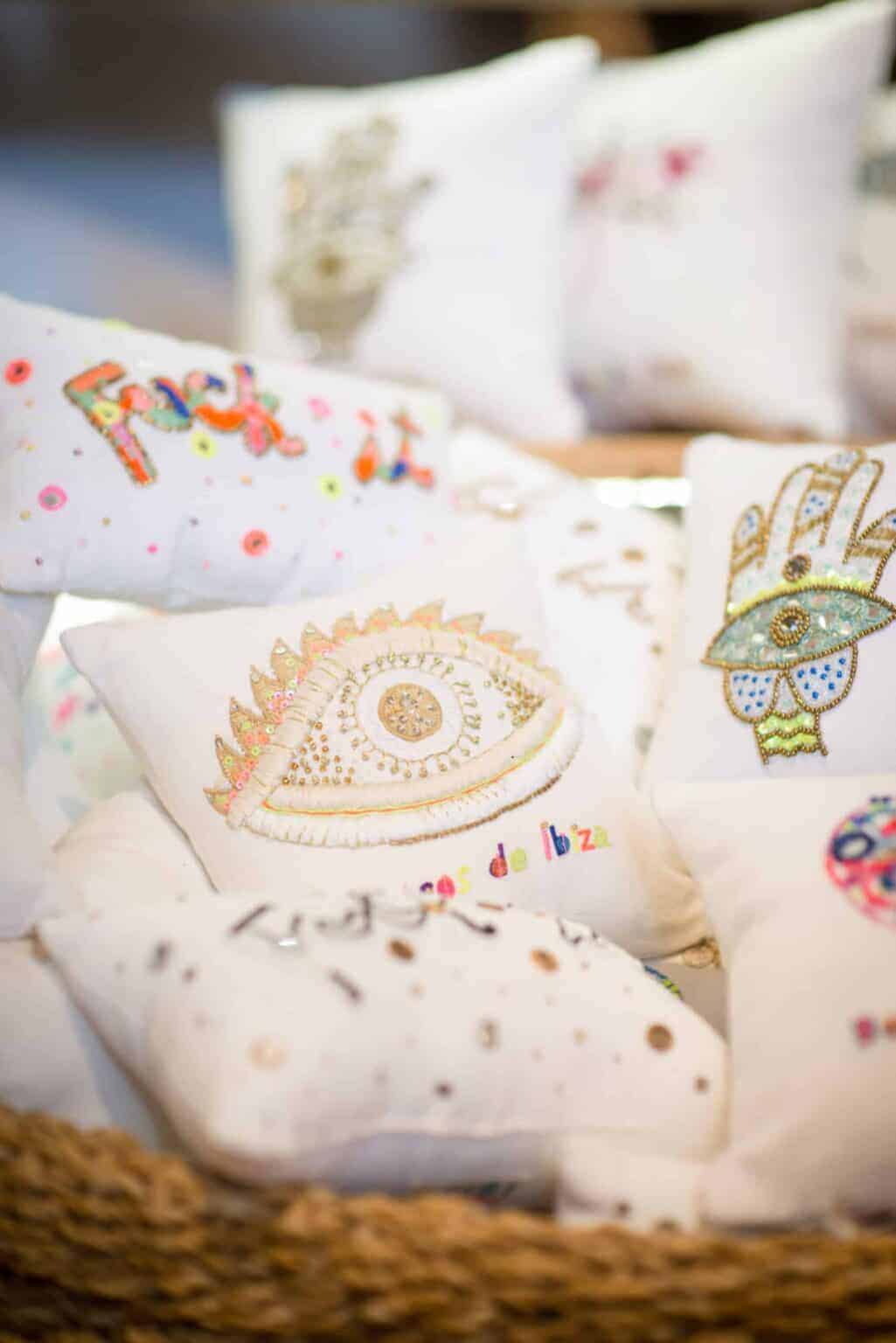 Bright embroidered cushions with intricate designs at La Galeria Elefante, emphasizing artisanal craftsmanship.