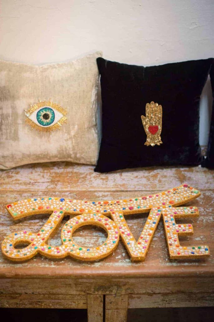 Vibrant embroidered cushions with eye and hand designs at La Galeria Elefante, emphasizing unique artisan home decor and vibrant textile art.