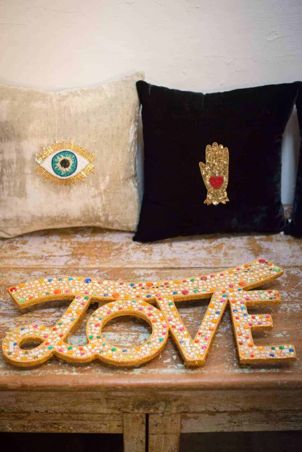 Vibrant embroidered cushions with eye and hand designs at La Galeria Elefante, emphasizing unique artisan home decor and vibrant textile art.