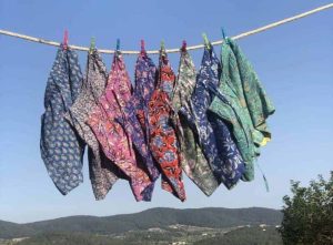 Vibrant batik clothing displayed on a clothesline against a clear blue sky. at La galeria Elefante