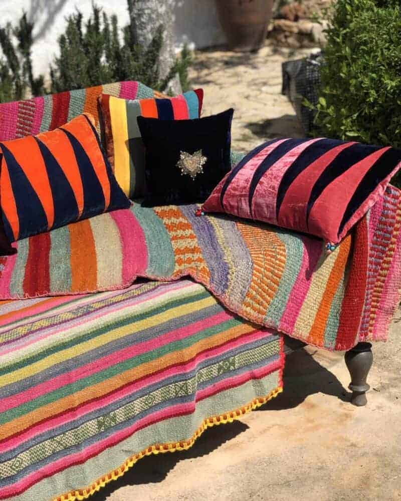 Colorful striped and embroidered cushions on outdoor sofa, perfect for boho patio decor from La galeria elefante