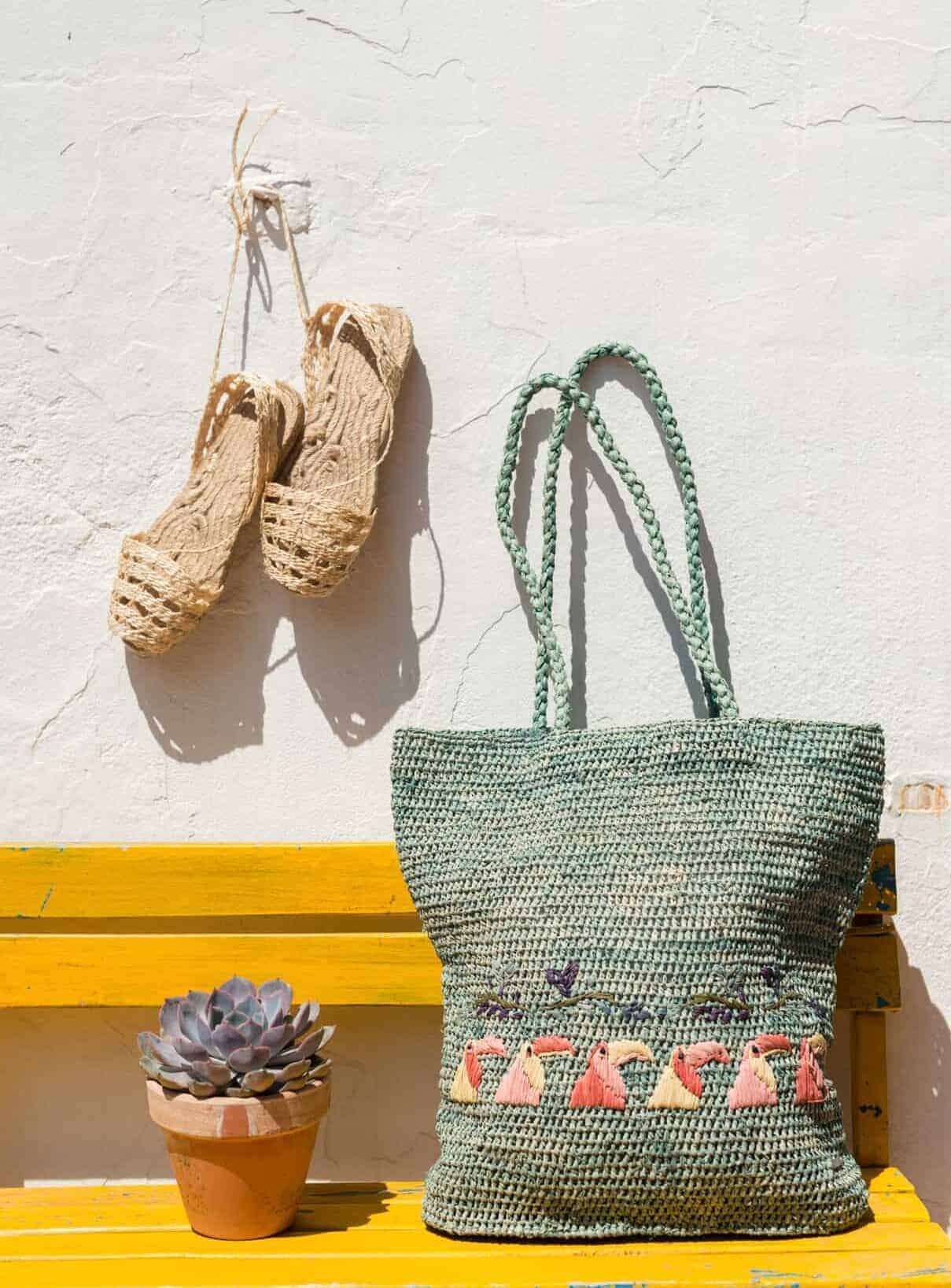 Colorful woven tote bag with embroidered flamingos on yellow bench in La Galeria Elefante Ibiza - Atzaro fashion show Ibiza