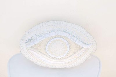 cushion in the shape of an eye with white embroidery