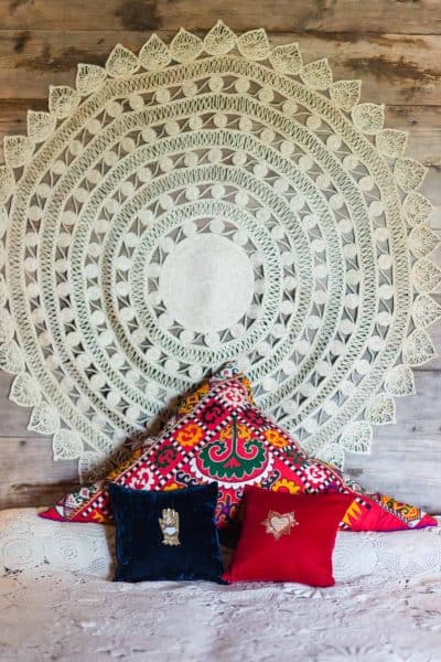round jute wall hanging above a bed with cushions