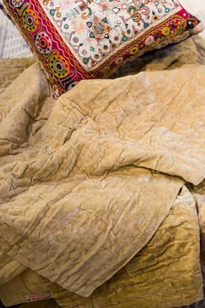 sandy coloured velvet bedspread with embroidered cushion