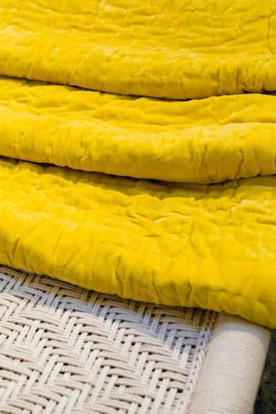folded yellow velvet bedspread on a macrame bed