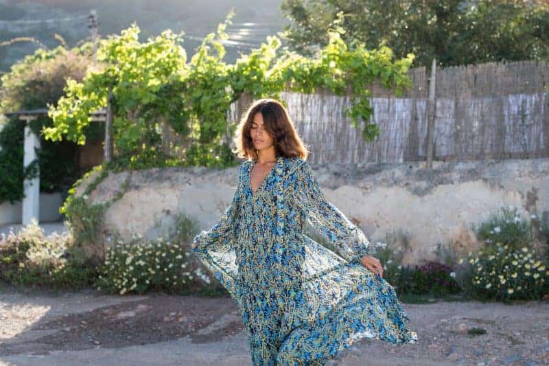 Elegant woman in a flowing floral dress at La Galeria Elefante vineyard, scenic outdoor setting with lush greenery and rustic backdrop, perfect for wine tours and vineyard experiences.