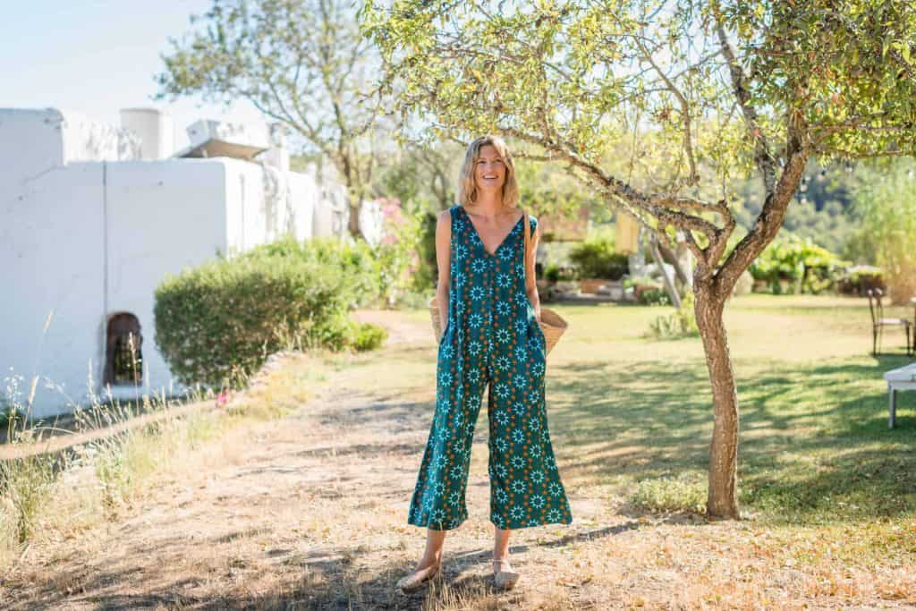 La Galeria Elefante Ibiza Woman in vibrant bohemian jumpsuit standing outdoors in Ibiza with trees and greenery.