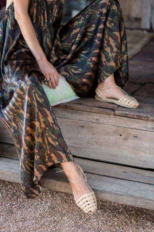 La Galeria Elefante Ibiza Woman in bohemian camouflage dress and woven espadrilles sitting on wooden steps.