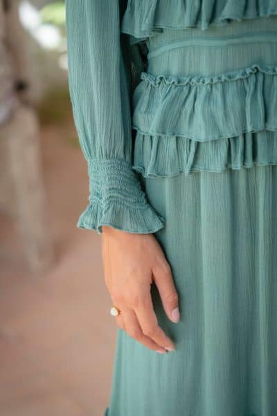 ruffle detail on cuffs and waist of a teal coloured dress