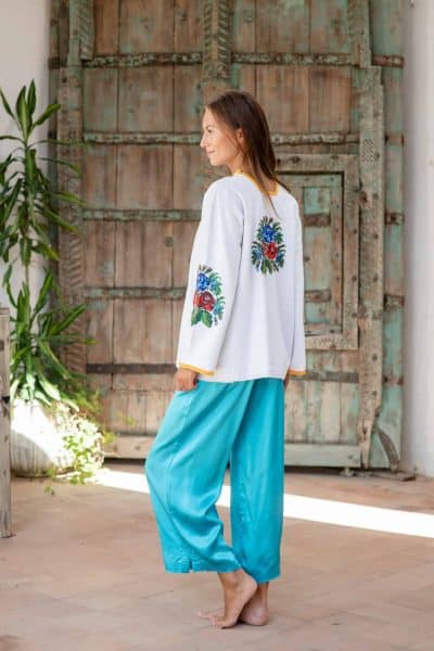 white long sleeve top with beaded floral embroidery worn with blue silk trousers