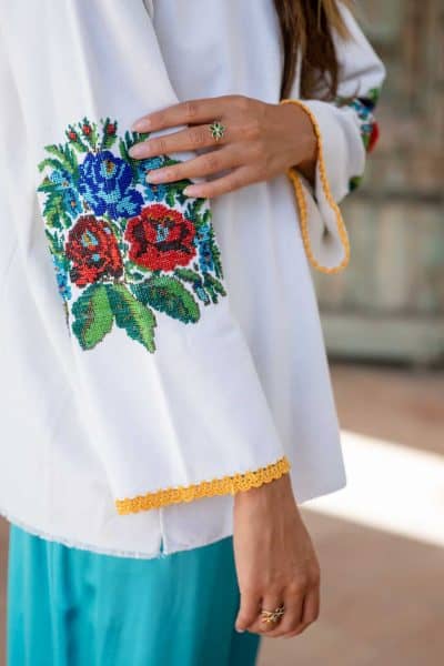 beaded floral embroidery on the elbows of a long sleeve white top