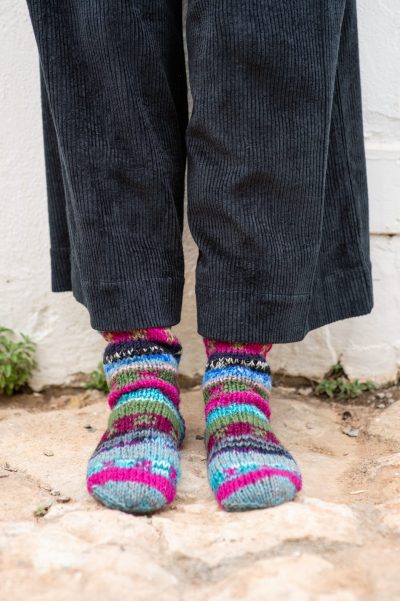 multicoloured wool socks peeping out from corduroy trousers