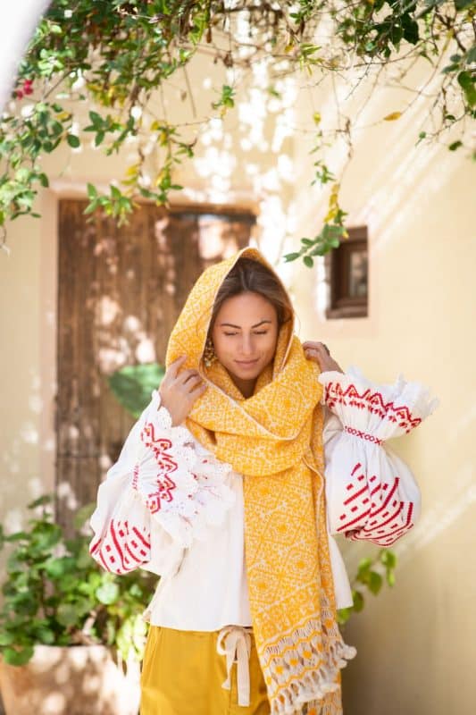 Model wears a yellow embroidered wool shawl with a vintage white red and yellow blouse and yellow trousers