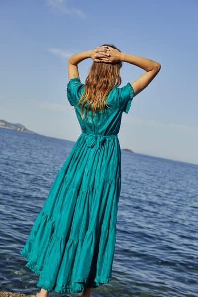 Model wearing a floor length green silk dress with short sleeves back view