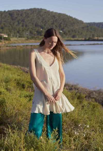 Model wearing green silk trousers with a cream silk dress with embroidered butterflies
