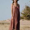 Model wearing a strappy floor length starry hand block print brown cotton dress with a hat in a field