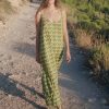 Model wears a floor length strappy cotton dress in a green print in a field