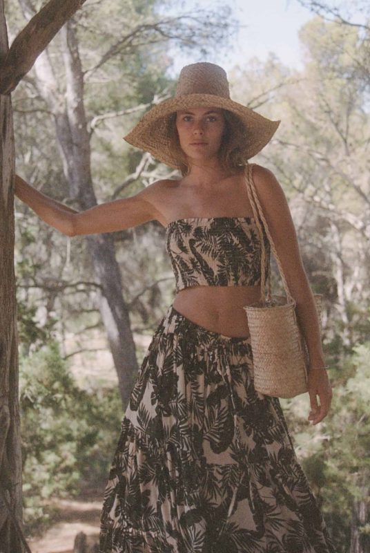 Close up of model in a matching skirt and boob tube top in a green and cream leaf print with a straw hat