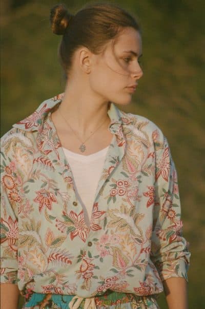 Close up of a model wearing a turquoise floral shirt profile