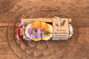 Mini Sahumo and Palo Santo sticks with colorful flower decorations, placed on a rustic wooden surface, ideal for spiritual cleansing and aromatic rituals.