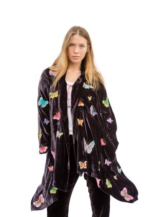 La Galeria Elefante Ibiza Young woman wearing velvet jacket with colorful butterfly embroidery, Ibiza bohemian style.