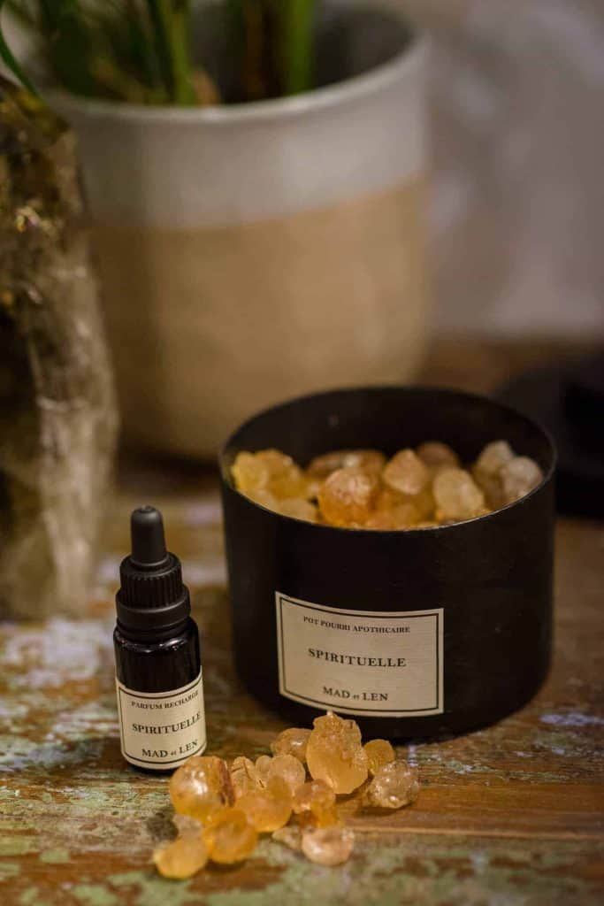 La Galeria Elefante Ibiza Aromatherapy oil bottle and amber crystals in a black container on wooden surface.