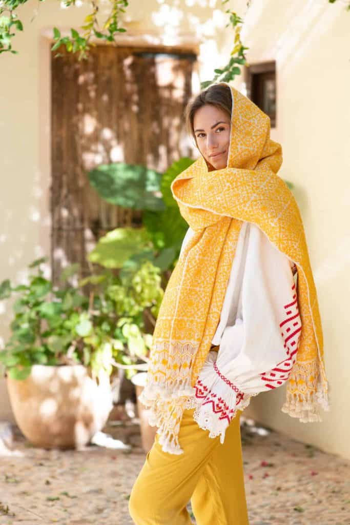 La Galeria Elefante Ibiza Fashionable woman wearing a yellow scarf and white dress in Ibiza garden.