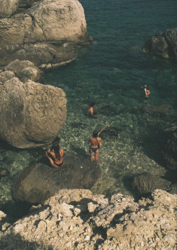 La Galeria Elefante Ibiza People enjoying a swim in clear rocky coastal waters near Ibiza.