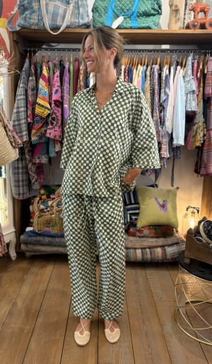 La Galeria Elefante Ibiza Woman in green and white patterned loungewear in boutique with colorful clothes and accessories.