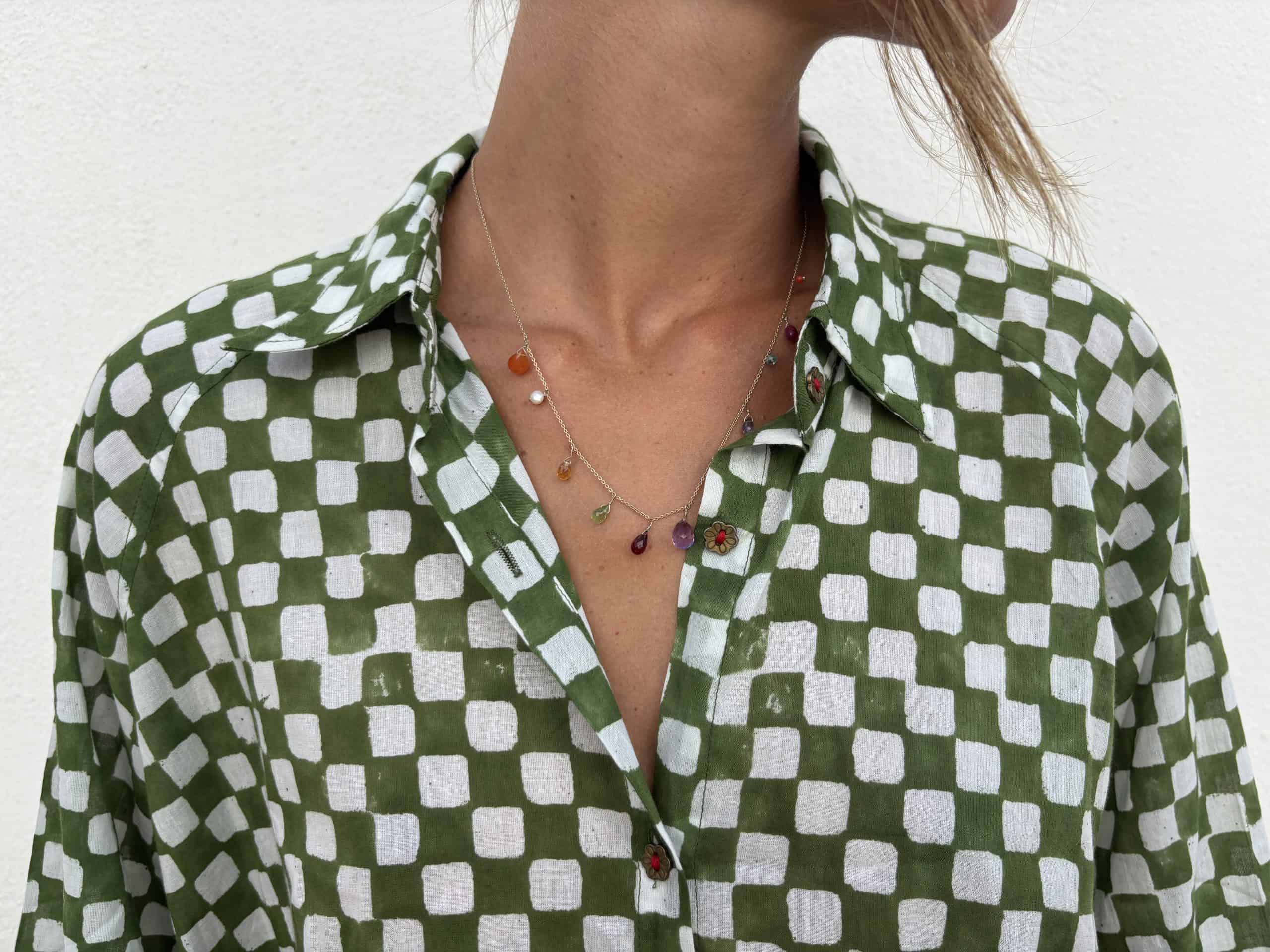 La Galeria Elefante Ibiza Woman wearing a green and white checkered artisan blouse with colorful jewelry.