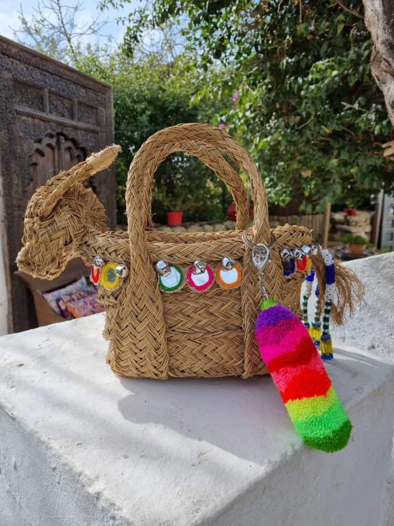 La Galeria Elefante Ibiza Handwoven straw handbag with colorful accessories and jewelry, Ibiza bohemian style.