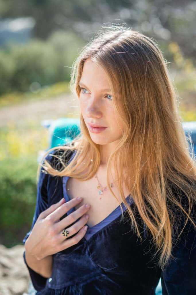 La Galeria Elefante Ibiza Portrait of a woman with long blonde hair outdoors, wearing a navy dress and jewelry.